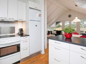 A modern kitchen with white cabinetry, a stainless steel range hood, and a built-in oven.