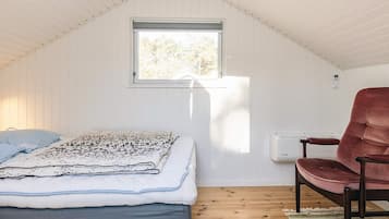 Un dormitorio con cama, ventana, una silla y un radiador.