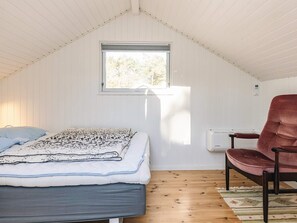 Un dormitorio con cama, ventana, una silla y un radiador.