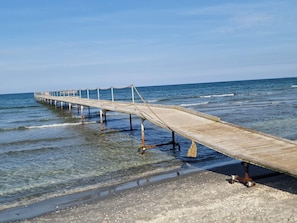 Un muelle de madera que se adentra en el océano, con agua cristalina y un mar en calma.