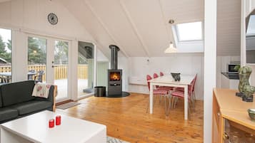 A cozy living area with a fireplace, a dining table with chairs, and a sofa.