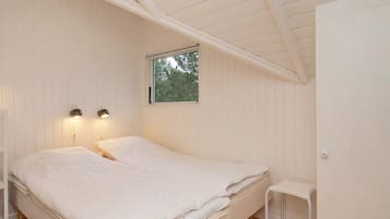 A bedroom with a single bed, two bedside lamps, a window, and a small white chair.