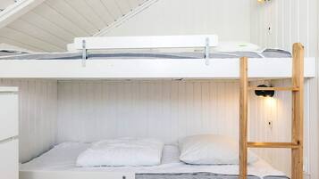 Ein Etagenbett mit einer Leiter, weißer Bettwäsche und einer Wandlampe.