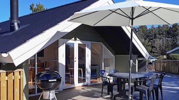 A covered patio with a barbecue grill, outdoor table, and chairs.