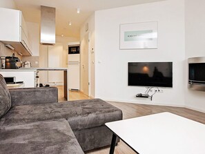 A modern living room with a grey sofa, a white coffee table, and a flat-screen TV mounted on the wall. - Holiday Home in Wendtorf (Wendtorf)