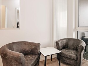 Quarto com duas poltronas e uma pequena mesa branca.