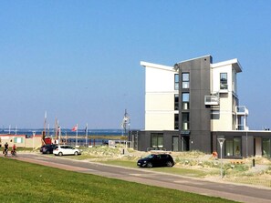 A modern building with a flat roof, large windows, and a balcony.