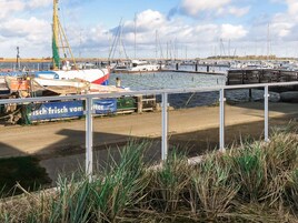Un puerto deportivo con barcos amarrados, un área verde al frente y un cielo despejado.