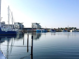 Un puerto deportivo con barcos amarrados, cielo despejado y edificios al fondo.