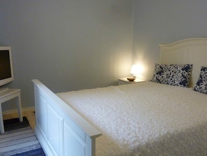 A bedroom with a bed, a bedside table, a lamp, and a television. - 2 Person Holiday Home in Solvesborg (Sölvesborg)