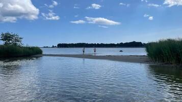 En stilla sjö med klart vatten och en sandstrand.