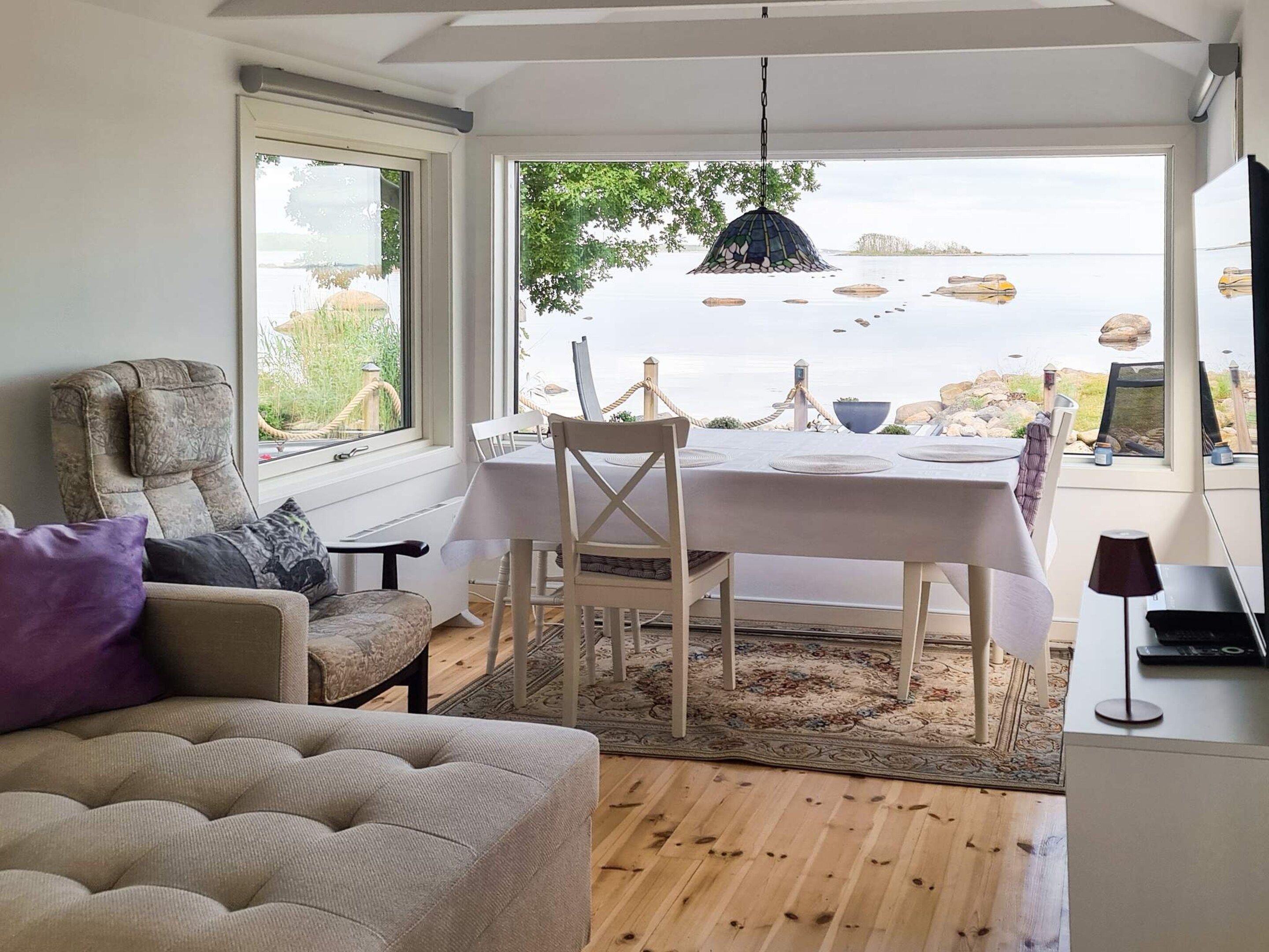 Ein Essbereich mit Meerblick, eine Couch und ein Tisch mit Stühlen.