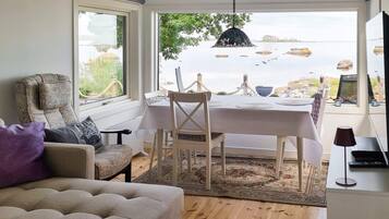 Ein Essbereich mit Meerblick, eine Couch und ein Tisch mit Stühlen.