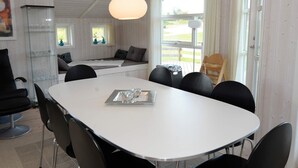 A dining area with a white table, black chairs, and a hanging light fixture.