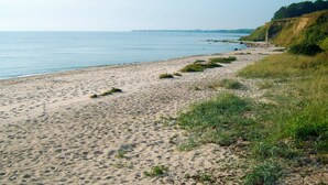 A sandy beach with grassy areas and a clear sky.
