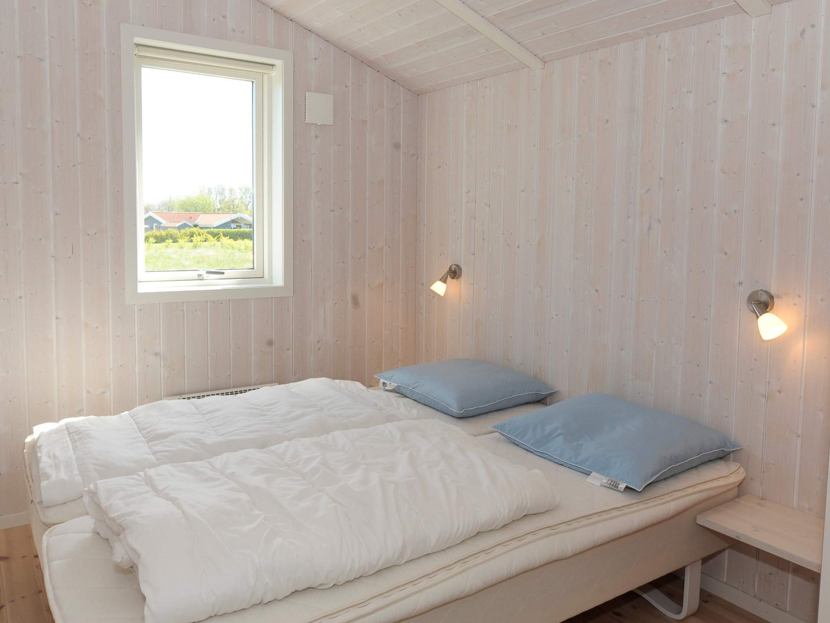 Quarto com cama, almofadas, janela e luzes na parede.
