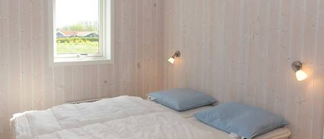 Quarto com cama, almofadas, janela e luzes na parede.