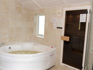 A bathroom with a large bathtub, a window, and a door leading to a shower area. - 4 Star Holiday Home in Sydals (Sydals)