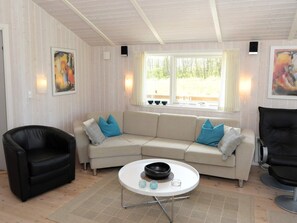 A living room with a beige sofa, black leather armchair, and a white coffee table with a bowl and glasses. - 4 Star Holiday Home in Sydals (Sydals)
