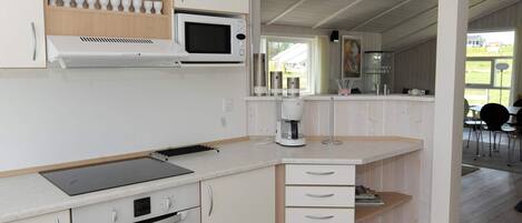 A modern kitchen with white cabinetry, a built-in microwave, a coffee maker, and a laptop on the countertop.
