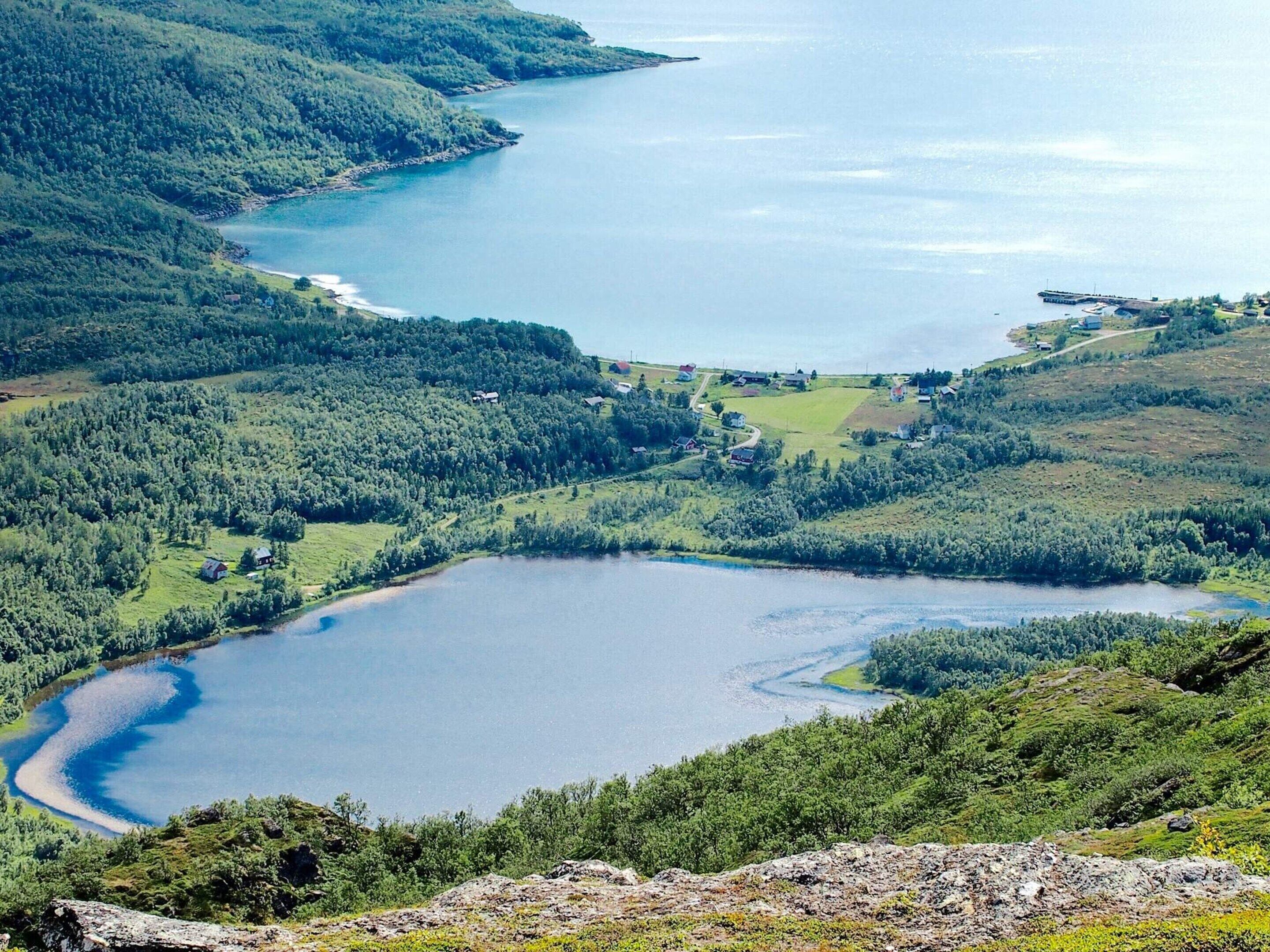 A lake surrounded by forested hills, a small dock, and scattered buildings.