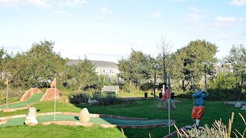 Ein Minigolfplatz mit Putting-Green, Sandfällen und einer Statue eines Golfspielers.