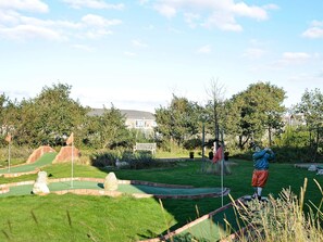 A miniature golf course with a putting green, sand traps, and a statue of a golfer. - 4 Person Holiday Home in Fano (Fano)