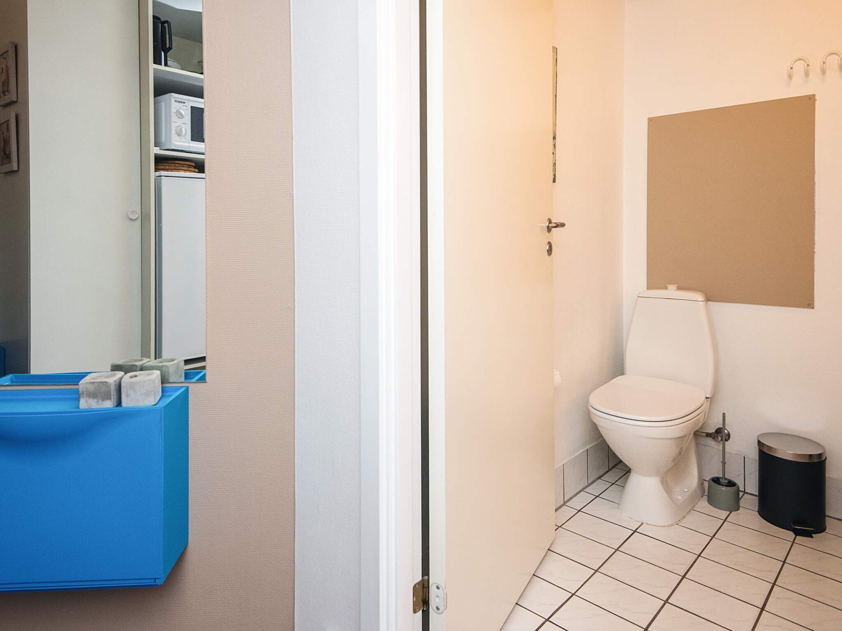 Un bagno con un water, un cestino e un mobiletto azzurro.
