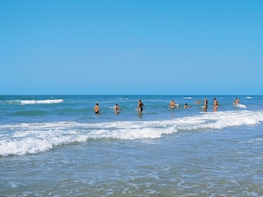 A beach with people swimming and walking in the water. - 4 Person Holiday Home in Fano (Fano)