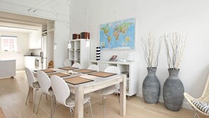 A modern dining area with a wooden table, white chairs, and a world map on the wall. - Seaside Escape in Bagenkop - By Traum Ferienwohnungen (Sydlangeland)