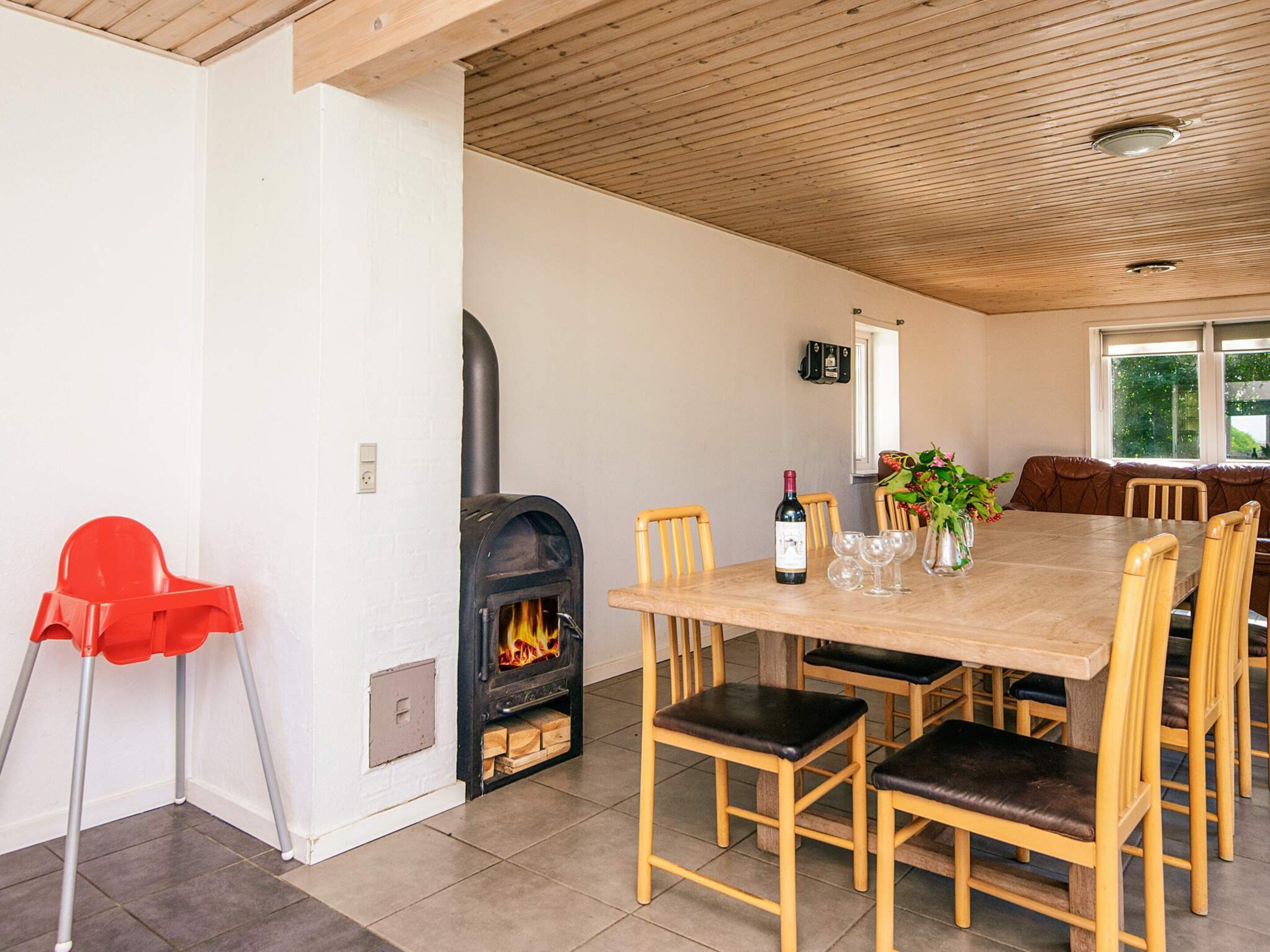 Un comedor con chimenea, sillas de madera, una mesa y una silla roja.