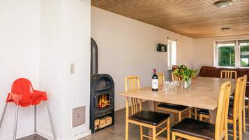 Un comedor con chimenea, sillas de madera, una mesa y una silla roja.