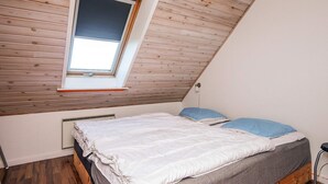 A bedroom with a sloped ceiling, a skylight, a bed with white and grey bedding, and a radiator below the window. - 12 Person Holiday Home in Bredebro (Bredebro)