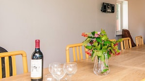 A dining table with a wine bottle, glasses, and a vase with flowers. - 12 Person Holiday Home in Bredebro (Bredebro)