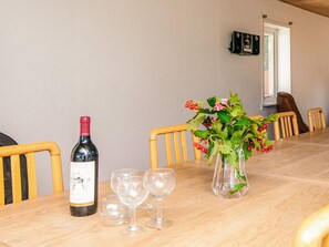 A dining table with a wine bottle, glasses, and a vase with flowers. - 12 Person Holiday Home in Bredebro (Bredebro)