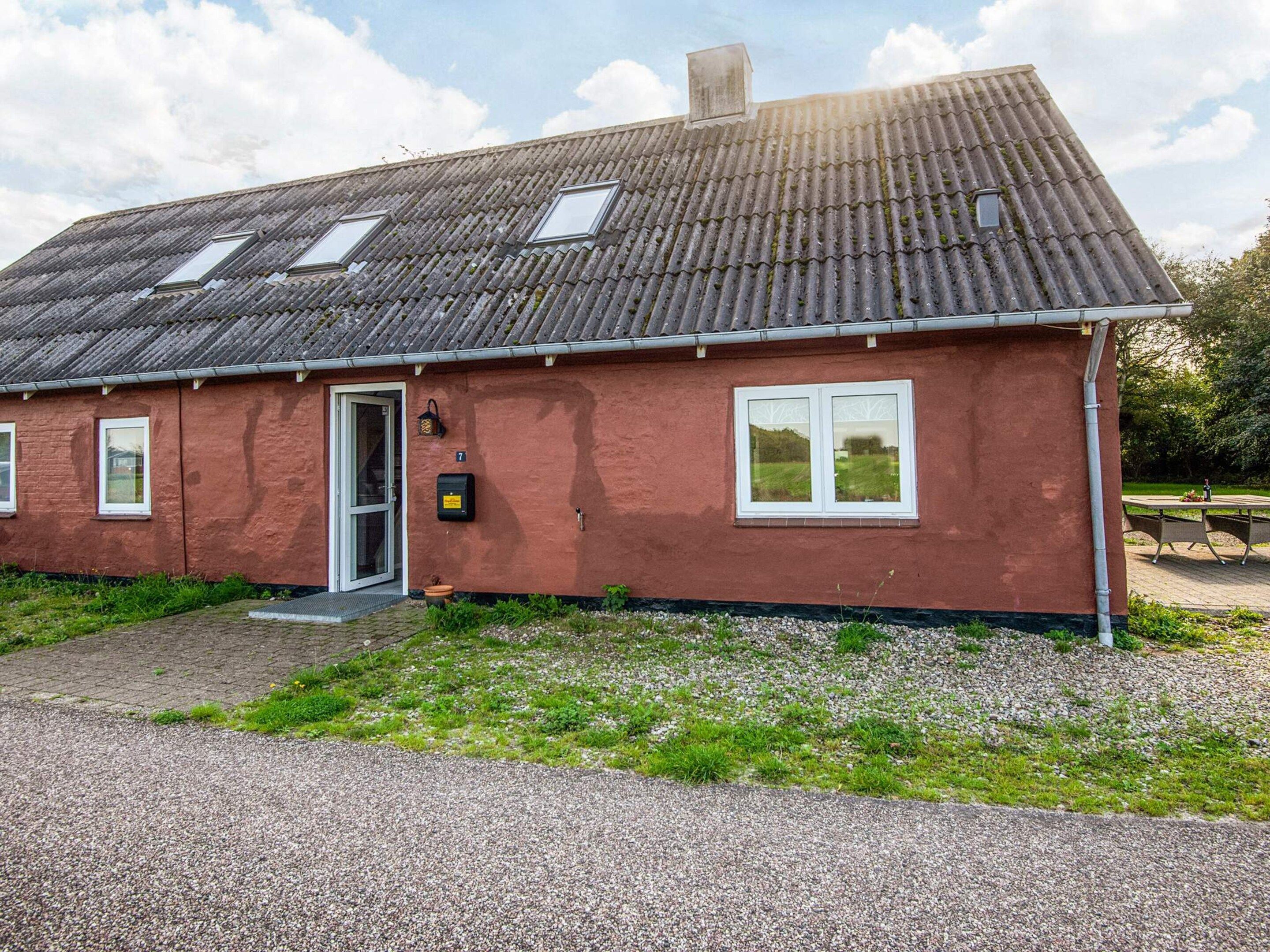 A red building with a tiled roof, a door, and two windows.