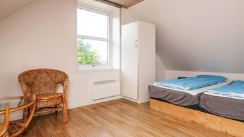 Un dormitorio con cama, una silla, un armario y una ventana.
