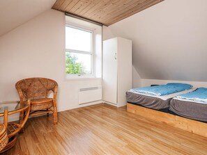 A bedroom with a bed, a chair, a wardrobe, and a window. - 12 Person Holiday Home in Bredebro (Bredebro)