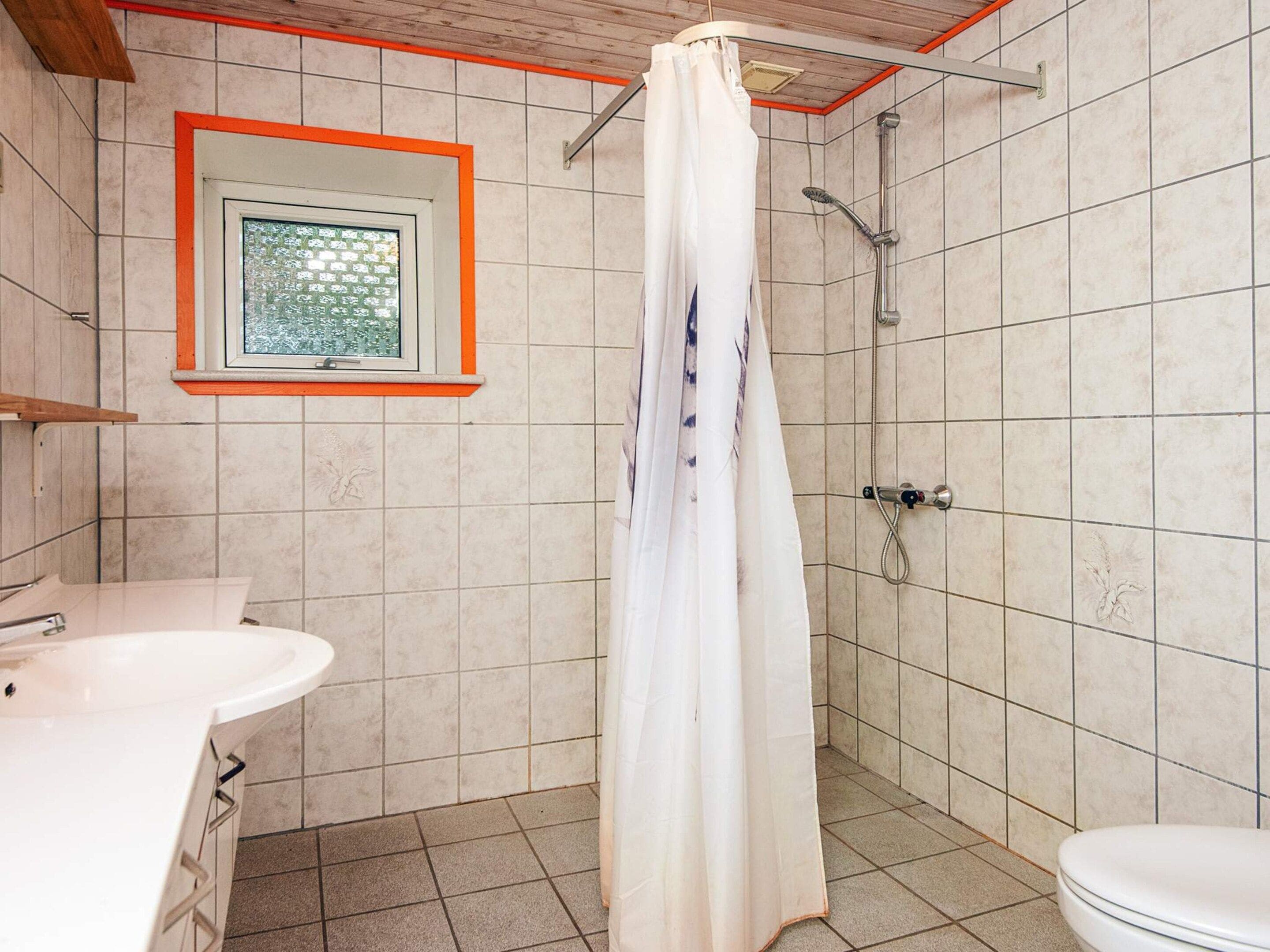 A bathroom with a shower, a toilet, and a sink.
