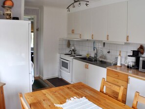 A kitchen with white cabinets, a wooden table, and a refrigerator. - 5 Person Holiday Home in Arvika (Arvika)