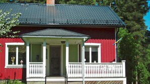 Une maison rouge avec un porche blanc et un toit noir.