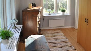 A room with a wooden bench, radiator, window with plants, and a door.