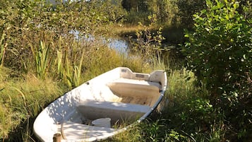 A small boat stranded in a grassy area near a body of water.