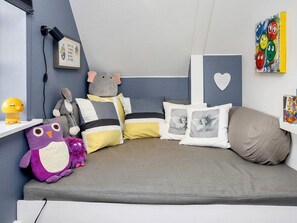 A cozy bedroom with a bed, pillows, stuffed toys, a wall clock, and a framed picture. - 6 Person Holiday Home in Lokken (Lokken)