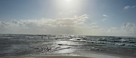 A beach with waves and a clear sky.