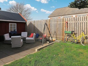 Une terrasse avec des meubles en osier, un vélo et une clôture en bois.