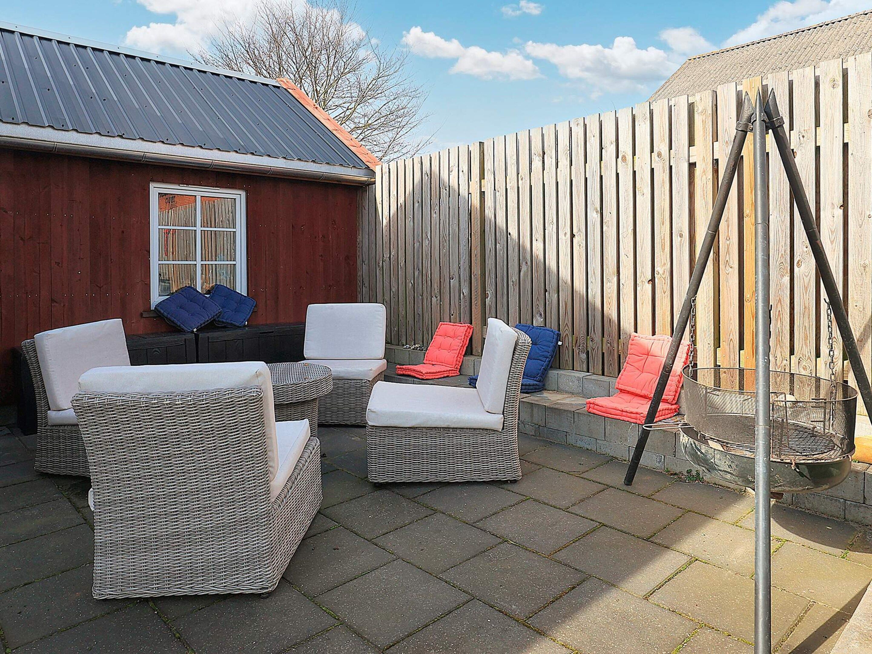 Une terrasse avec des meubles en osier et un barbecue.
