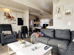 Uma sala de estar moderna com um sofá cinzento, uma mesa de centro e um quadro na parede.