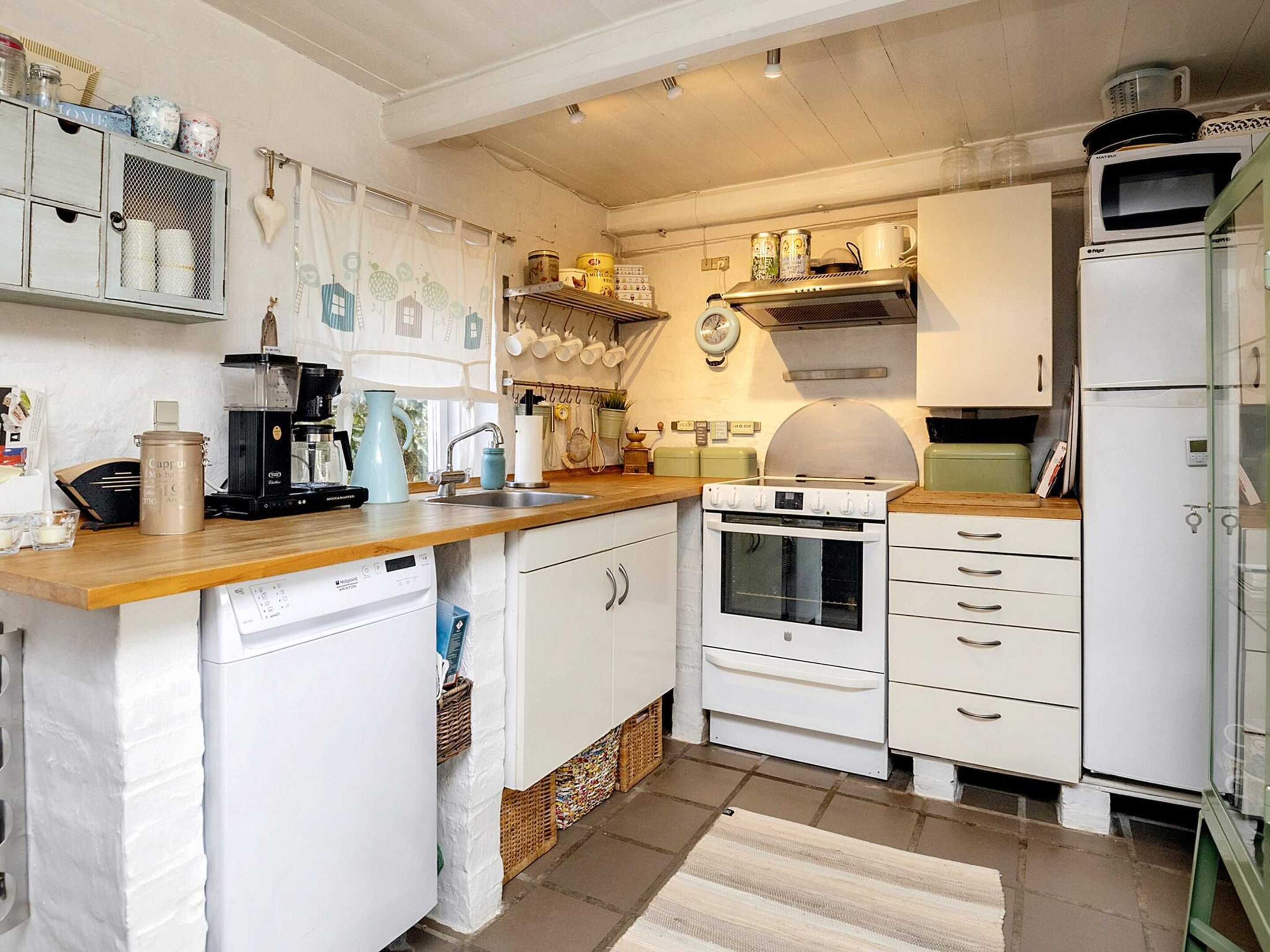 A compact kitchen with white cabinetry, a built-in oven, a microwave, and a sink.
