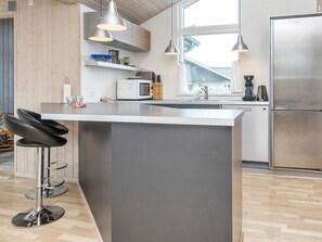 A modern kitchen with a central island, stainless steel appliances, and pendant lighting. - 5 Star Holiday Home in Harboore (Harboore)